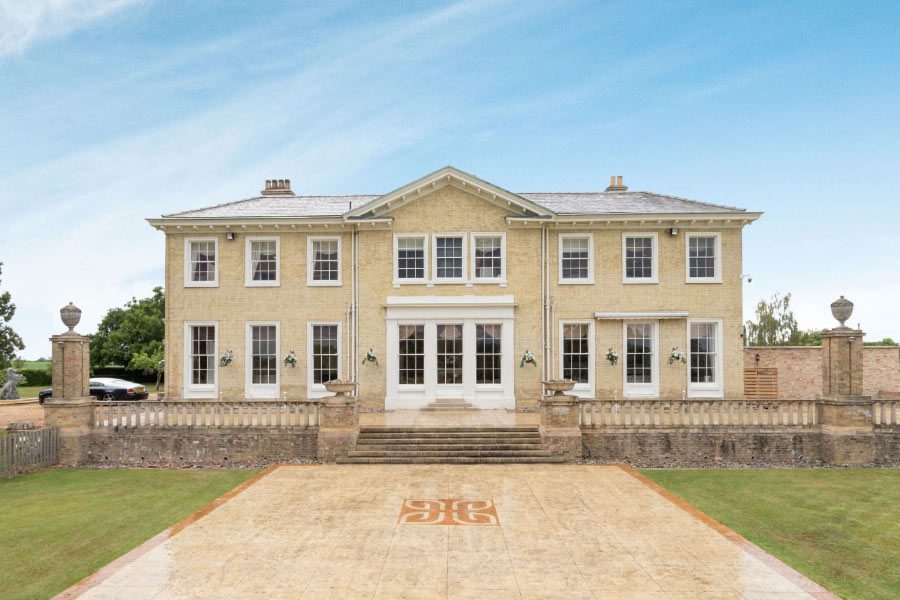 The yellow-brick Grade II listed exterior of Cosmetic Surgery Partners at Hemingford Park Hall, featuring classical architecture and extensive private grounds.